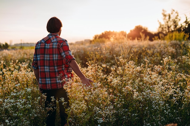 El hombre toca sus flores de mano en el campo.