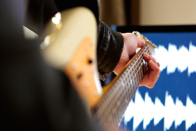 Hombre tocando acorde en la guitarra eléctrica