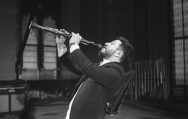 Hombre tocando el clarinete mientras está de pie en el estudio