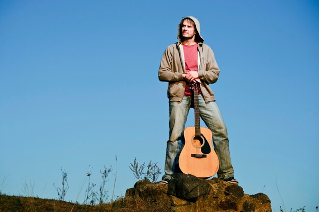 Hombre tocando la guitarra en el campo al atardecer.