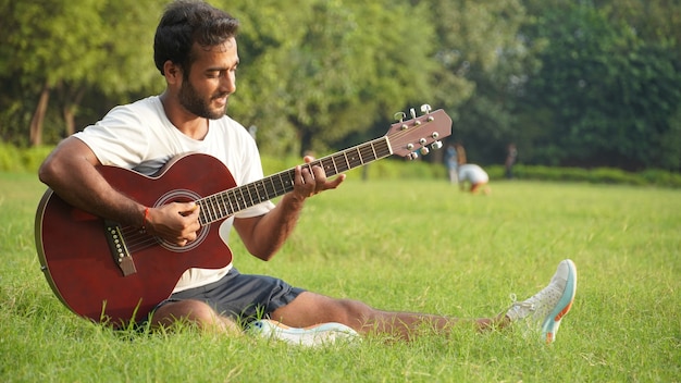 Foto hombre tocando la guitarra en el parque