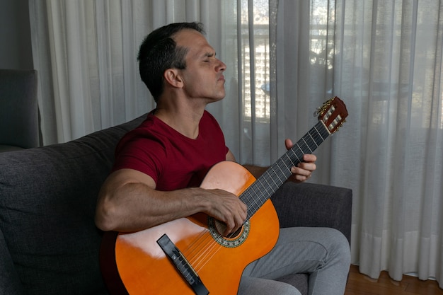 Hombre tocando la guitarra en la sala de estar y haciendo un solo.