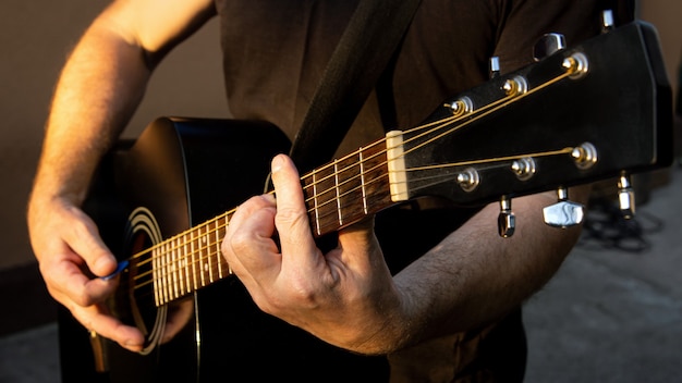 Un hombre tocando una melodía en una guitarra. De cerca