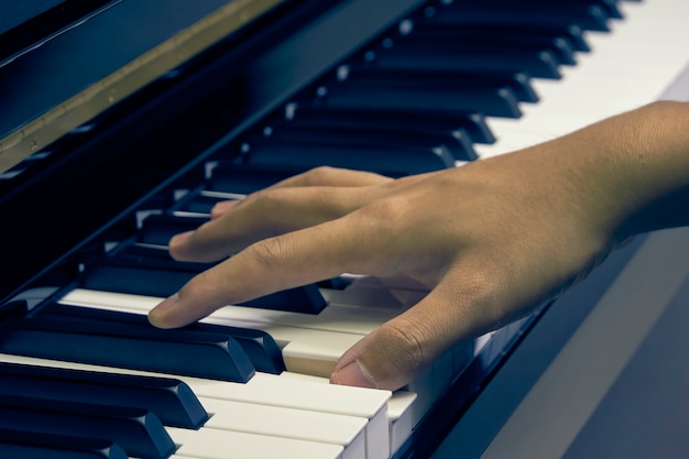 Hombre tocando el piano en el estudio con la mano borrosa