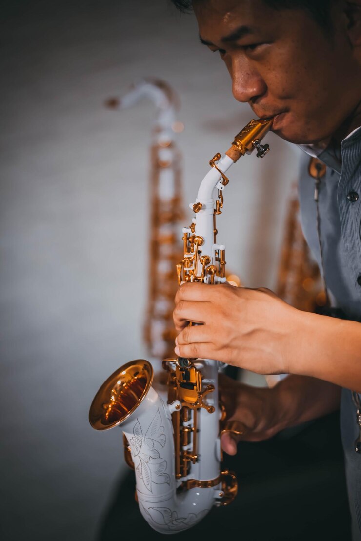 Foto hombre tocando el saxofón contra la pared