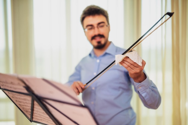 Foto hombre tocando el violín en casa está limpiando su instrumento