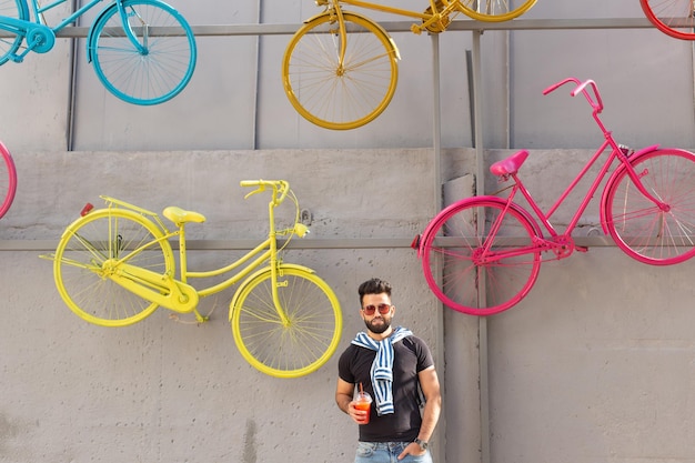 Foto hombre de toda la longitud con bicicleta de pie contra la pared