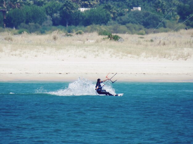 Foto hombre de toda la longitud haciendo kiteboard en el mar