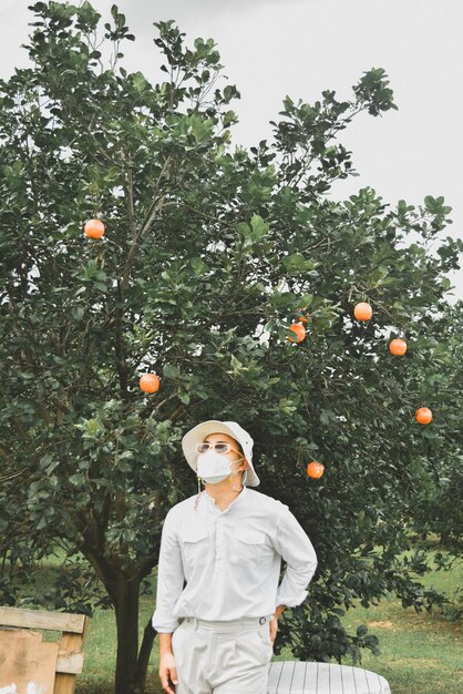 Foto el hombre de toda la longitud de pie por el árbol contra el cielo naranja