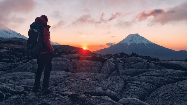 Hombre de toda la longitud de pie en el paisaje durante la puesta de sol