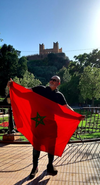 Foto hombre de toda la longitud sosteniendo una bandera roja contra el cielo