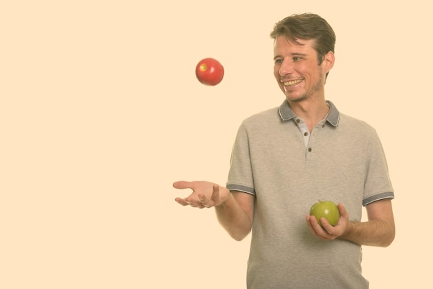 Foto hombre de toda la longitud sosteniendo una manzana contra un fondo blanco