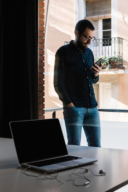 El hombre se toma un descanso del teletrabajo mirando su teléfono inteligente