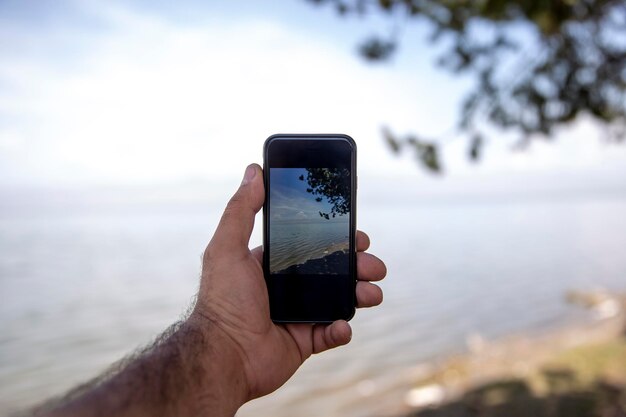 El hombre toma una foto con un teléfono inteligente en la naturaleza.