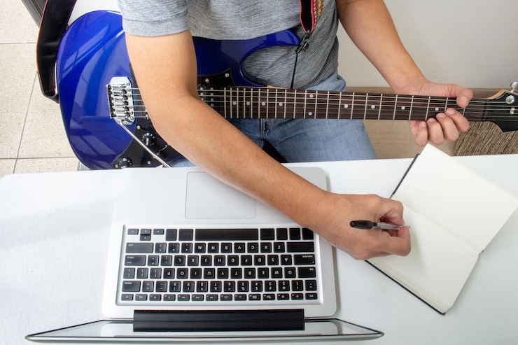 Foto el hombre toma notas de una clase de guitarra eléctrica en línea en casa