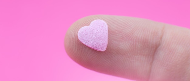 El hombre toma un pequeño corazón rosa sobre fondo rosa Concepto del día de San Valentín Amor y metraje romántico Hermoso fondo de pantalla cálido con amor Enfoque suave