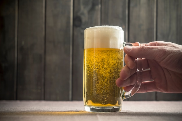 El hombre toma un vaso de cerveza de la mesa.