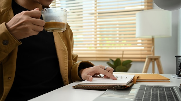 Hombre tomando café y leyendo un libro por la mañana.