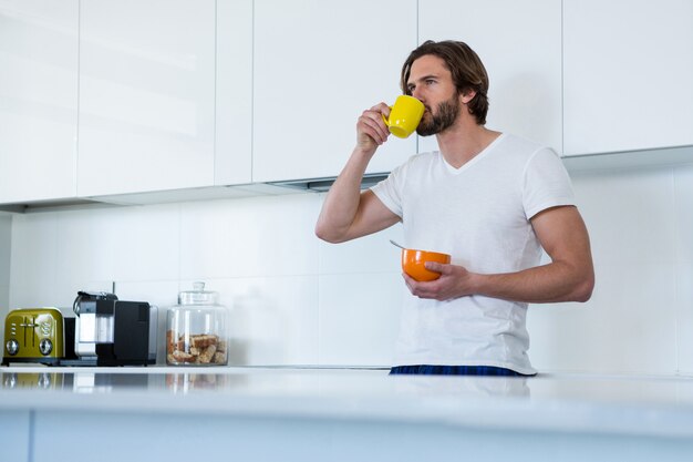 Hombre tomando café mientras desayunando en la cocina