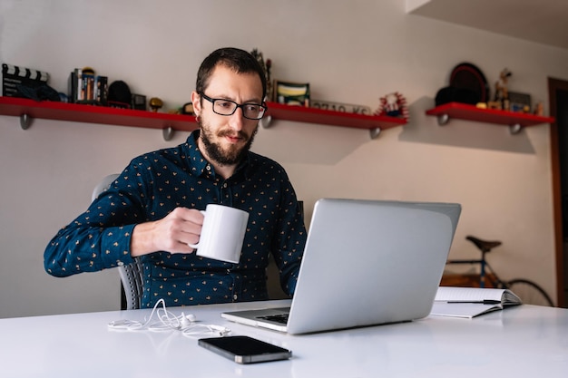 Hombre tomando un café mientras teletrabaja