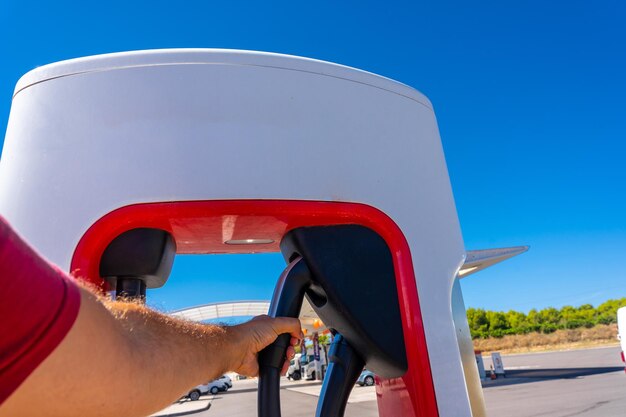 Un hombre tomando el cargador de coche eléctrico coches futuros movilidad ecológica no gasolina