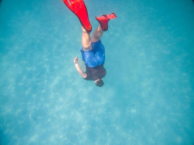 Hombre tomando una foto selfie bajo el agua con máscara de buceo