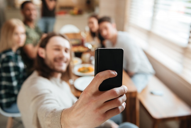 Hombre tomando una foto selfie con amigos en la cocina