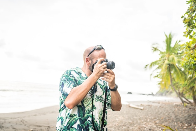 Hombre tomando fotografías con una cámara en una playa tropical