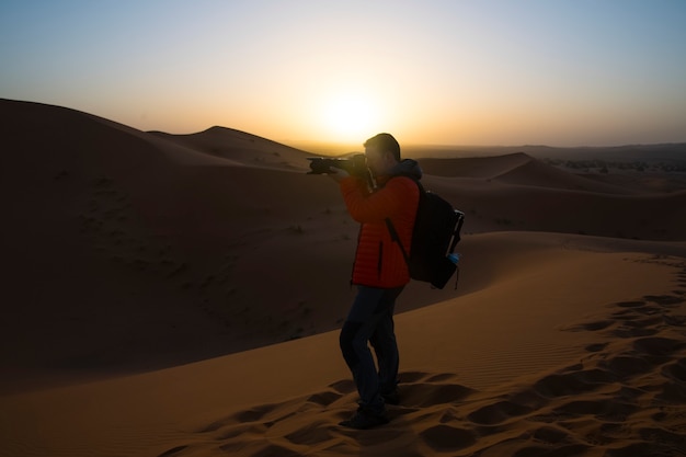 Hombre tomando fotos del amanecer en el desierto