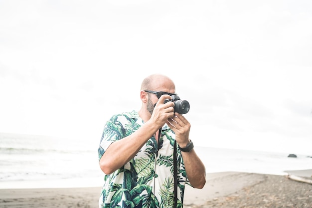 Hombre tomando fotos con cámara digital en una playa tropical