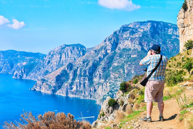 Hombre tomando fotos de hermosos paisajes en Path of Gods, mar Tirreno, costa de Amalfi, Italia