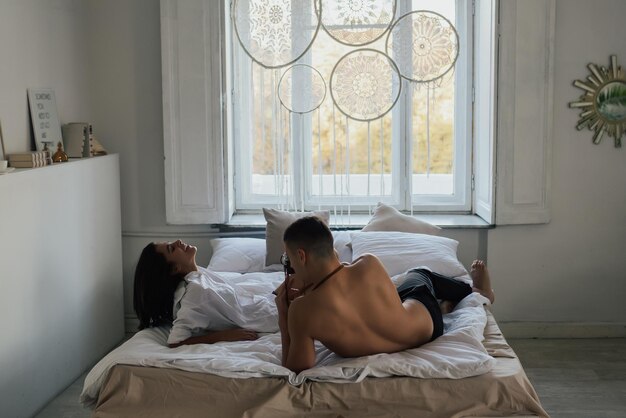 Hombre tomando fotos de su mujer en el dormitorio