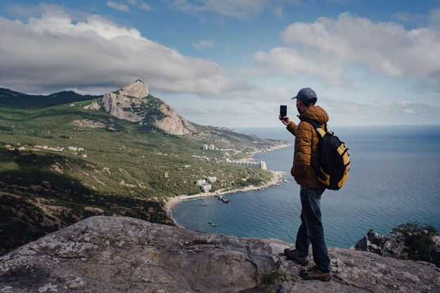 Hombre tomando fotos de una vista impresionante de las montañas con un teléfono inteligente