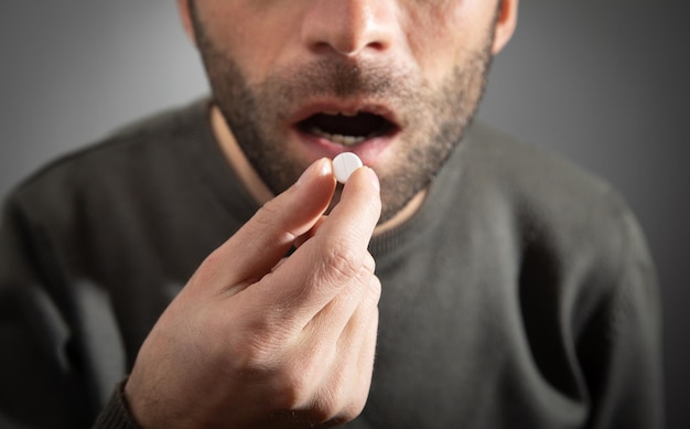 Hombre tomando pastillas medicinales en casa