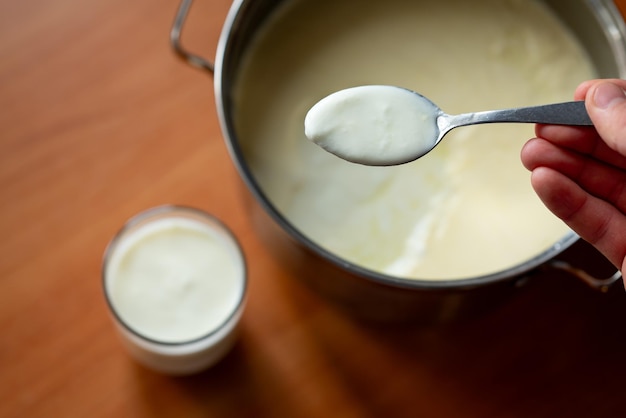 Foto hombre tomando un poco de yogur de la sartén a la taza para una comida comiendo productos lácteos saludables para tratar el estómago