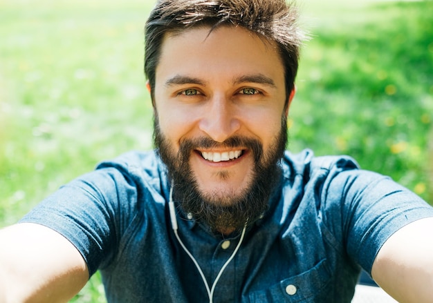 Hombre tomando selfie en el bosque sosteniendo el teléfono con las dos manos