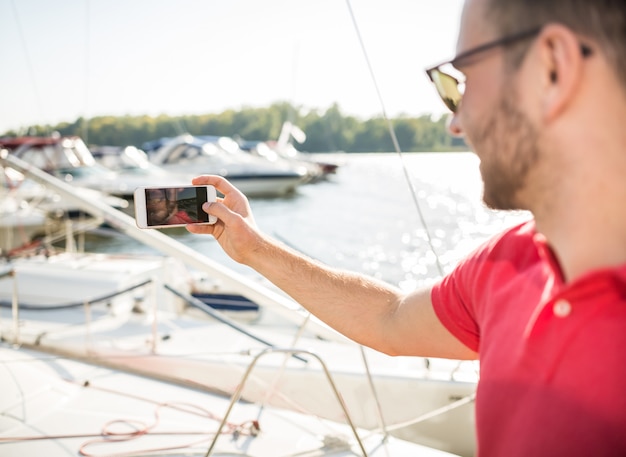 Hombre tomando selfie en gafas de sol y sonriendo.