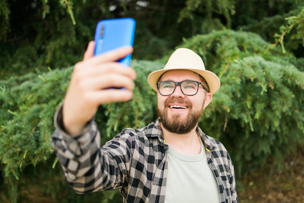 Hombre tomando selfie retrato sobre fondo de árbol feliz millennial guy disfrutando de las vacaciones de verano en ci