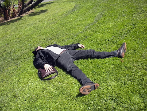 Foto hombre tomando el sol en el campo de hierba en el parque