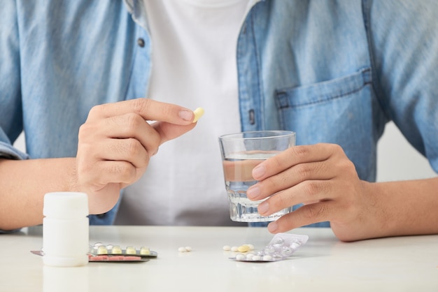 El hombre tomando sus pastillas en el sofá de la sala de estar