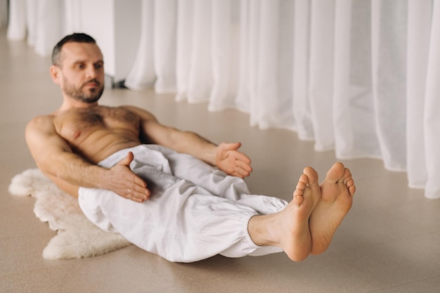 Un hombre con el torso desnudo hace yoga en una sala de fitness el concepto de un estilo de vida saludable