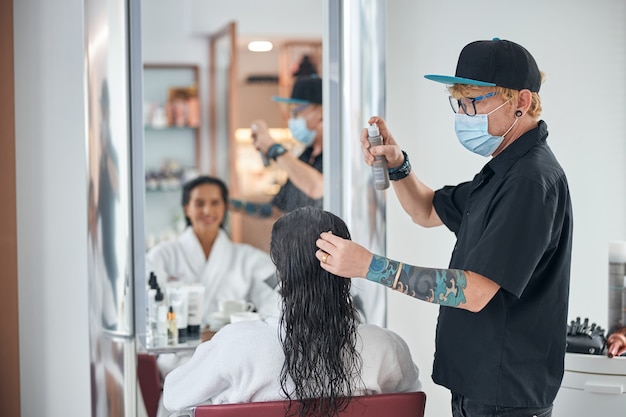 Hombre en un total de ropa negra cuidando el cabello.