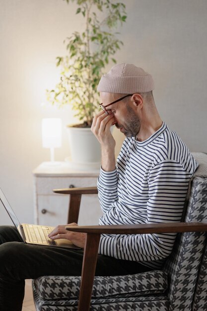 El hombre trabaja en una computadora portátil en casa, un diseñador independiente o un alto gerente trabaja en línea o ve un