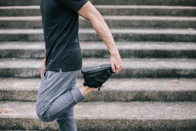 El hombre trabaja estirando las piernas para calentar antes de hacer ejercicio y subir escaleras.