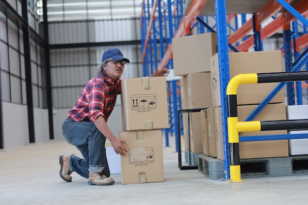 Hombre trabajador asiático levantar caja pesada en fábrica