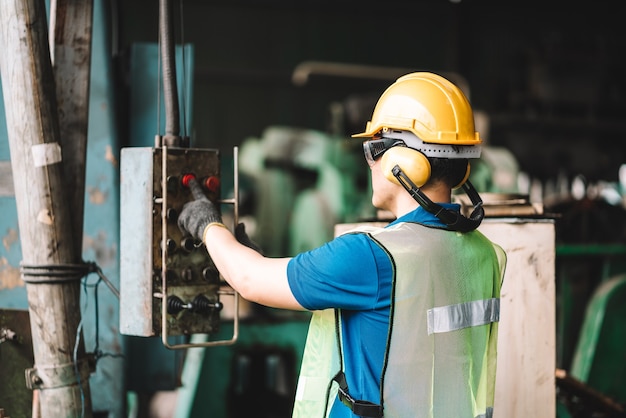 Hombre trabajador asiático que trabaja en ropa de trabajo de seguridad con casco amarillo con ordenador portátil digital.