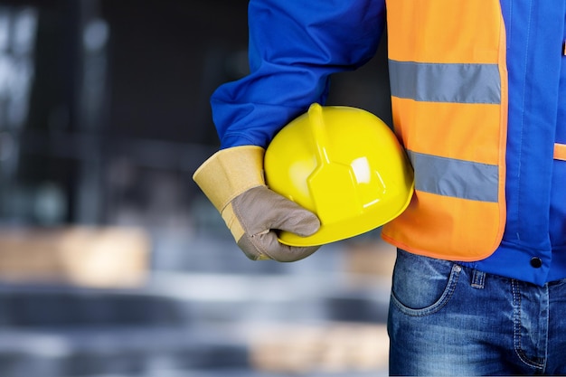 Foto hombre trabajador con un casco en las manos en el fondo