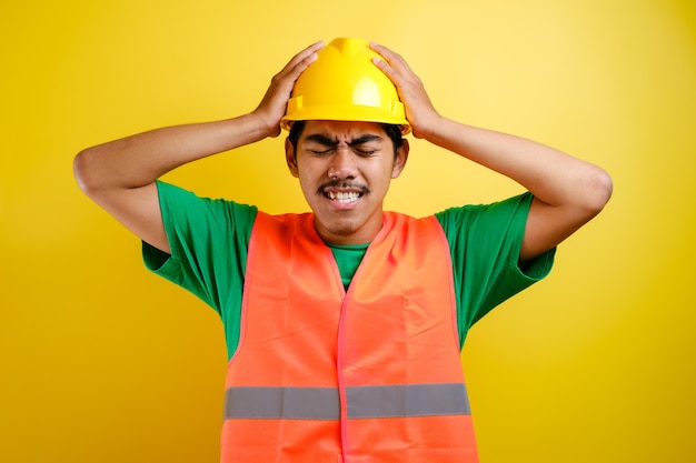 Hombre trabajador de construcción asiática con casco de seguridad estresado con la mano en la cabeza, conmocionado por la vergüenza y la cara de sorpresa, enojado y frustrado. Miedo y disgusto por error.
