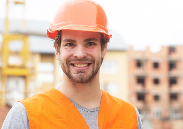 Hombre trabajador de la construcción en ropa de trabajo y un retrato de casco de construcción de constructor masculino positivo