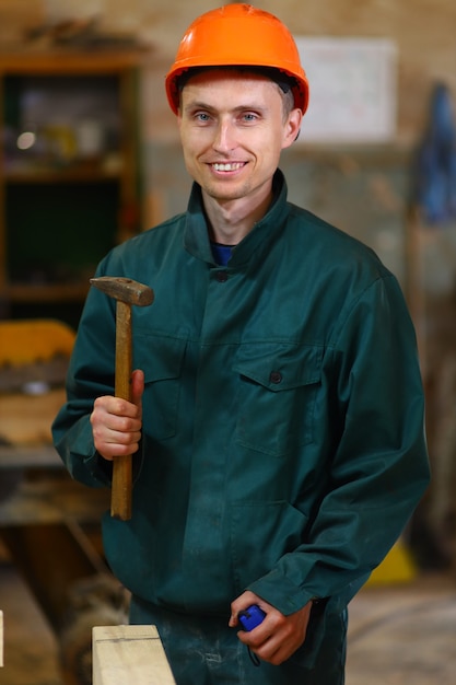 Hombre trabajador joven y guapo sosteniendo un martillo